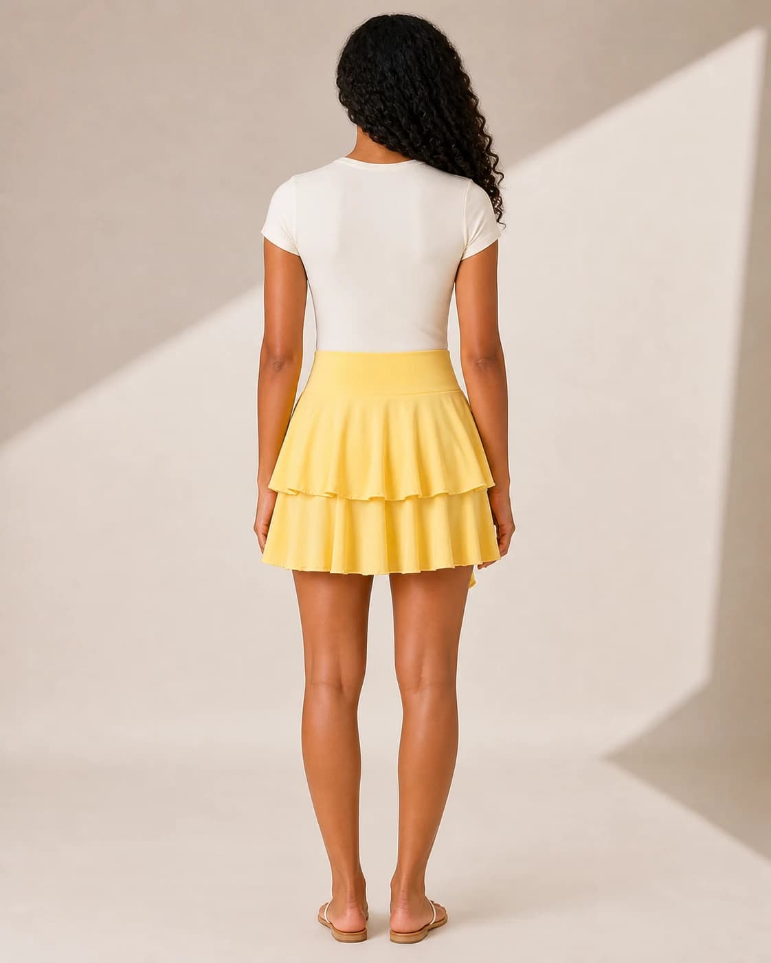 Falda mini amarilla volados cascada, vista de espalda en modelo