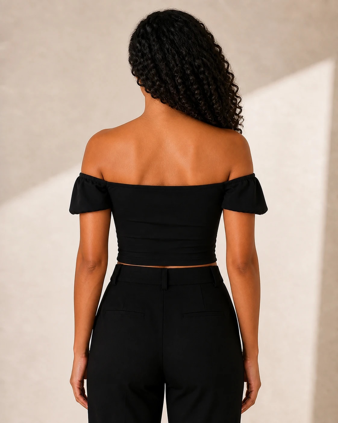 Top crop off shoulder frunce en negro, vista de espalda en modelo